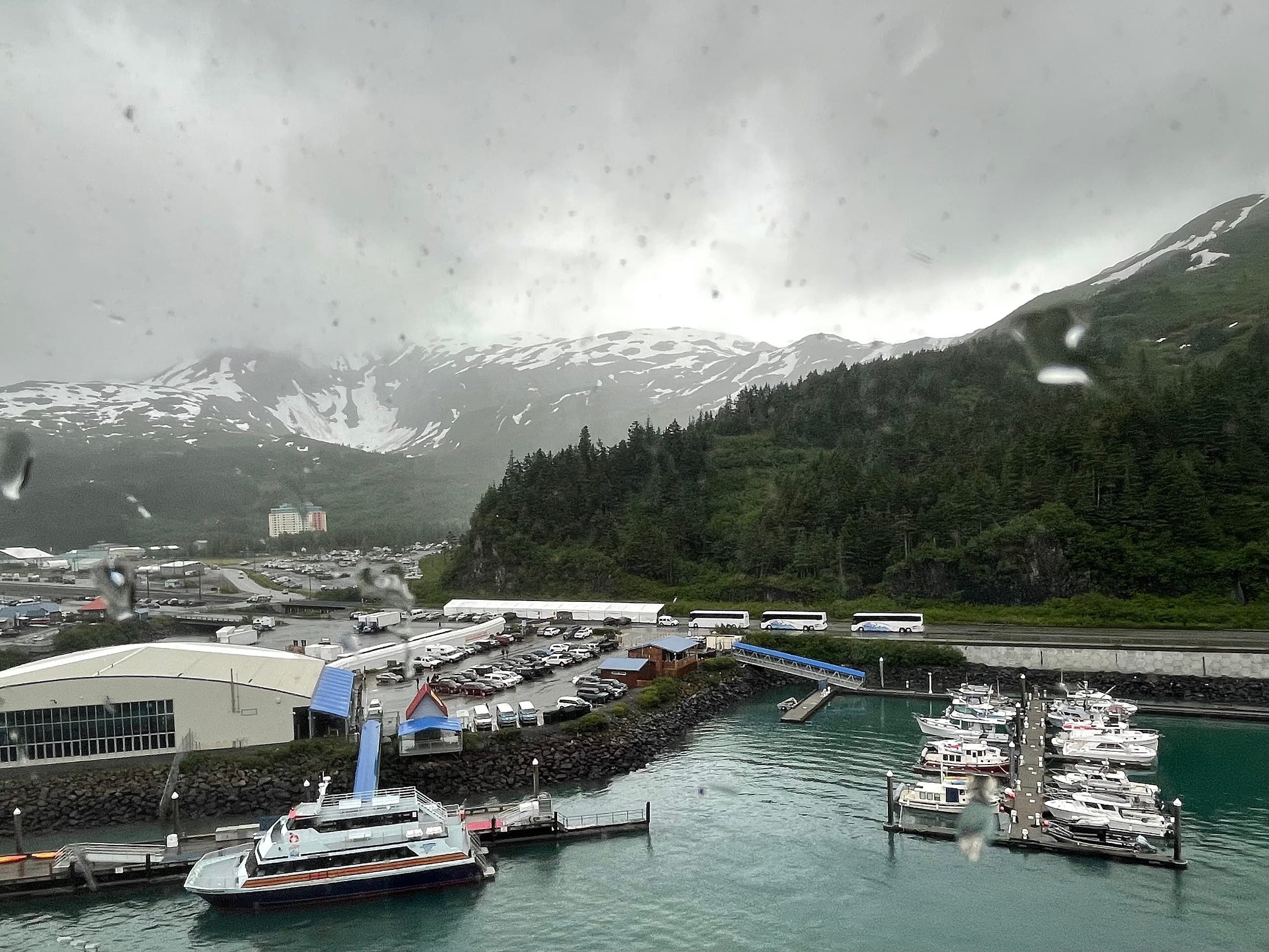 Harbor with tenders and yachts docked under misty Alaskan mountain town