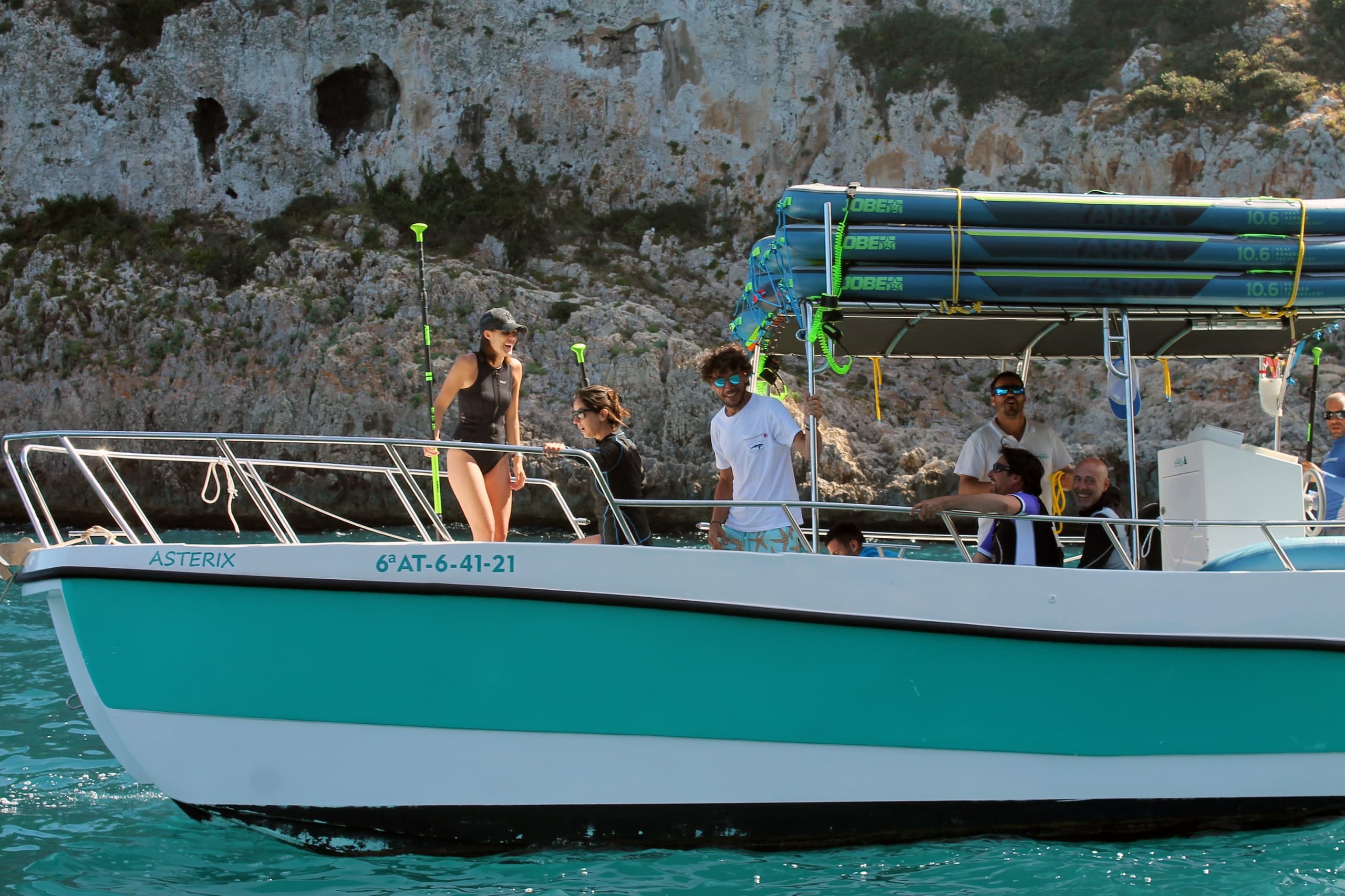 Small turquoise excursion boat cruising coastal waters with guests