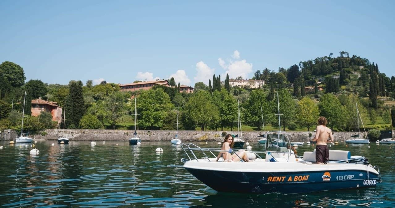 Passengers relaxing on rental boat near tree-lined shore