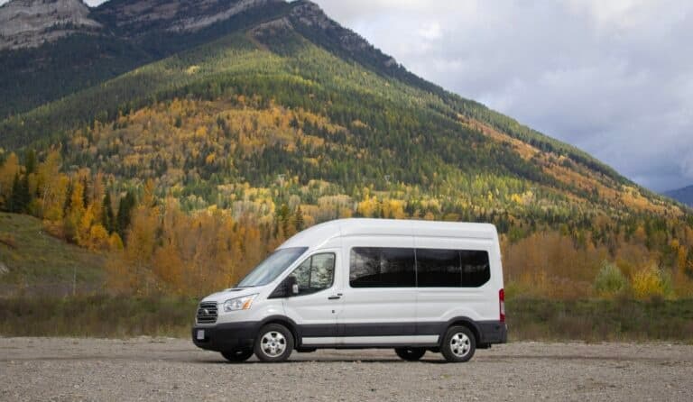 Shuttle van parked by colorful mountain valley in autumn