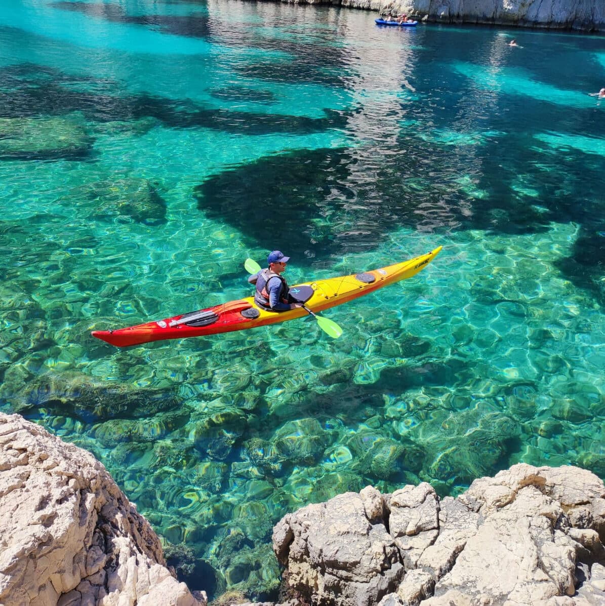 Solo kayaker paddling over crystal-clear Mediterranean water