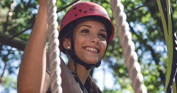 Smiling woman wearing climbing helmet on treetop rope course