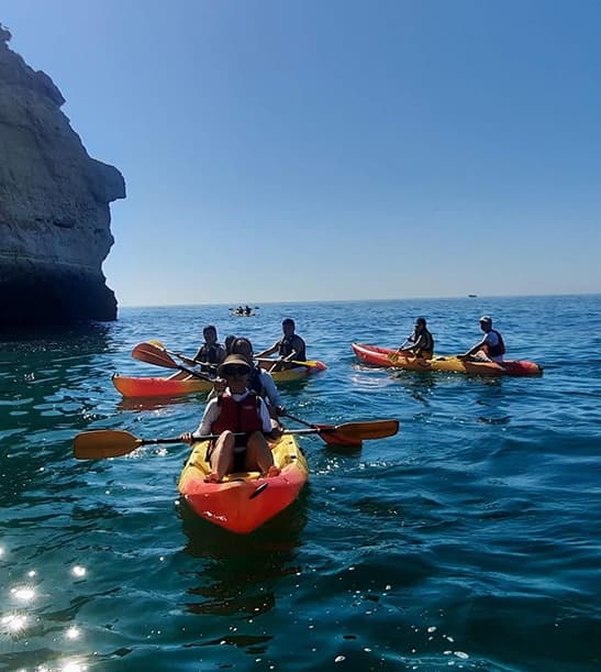 Group kayakers paddling in calm open sea near sheer cliffs