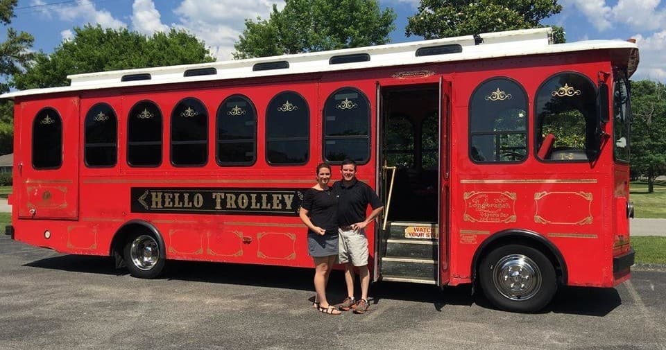 Red Hello Trolley parked near suburban park with passengers boarding
