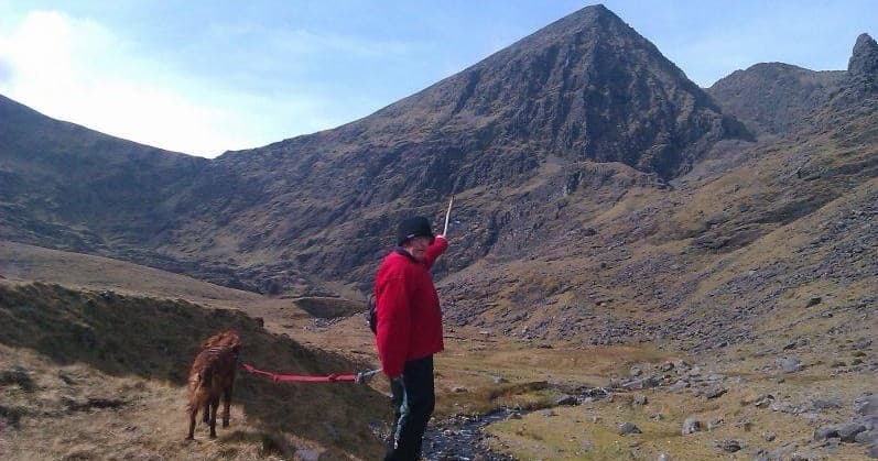 Hiker with dog on rugged mountain trail in Killarney, Ireland