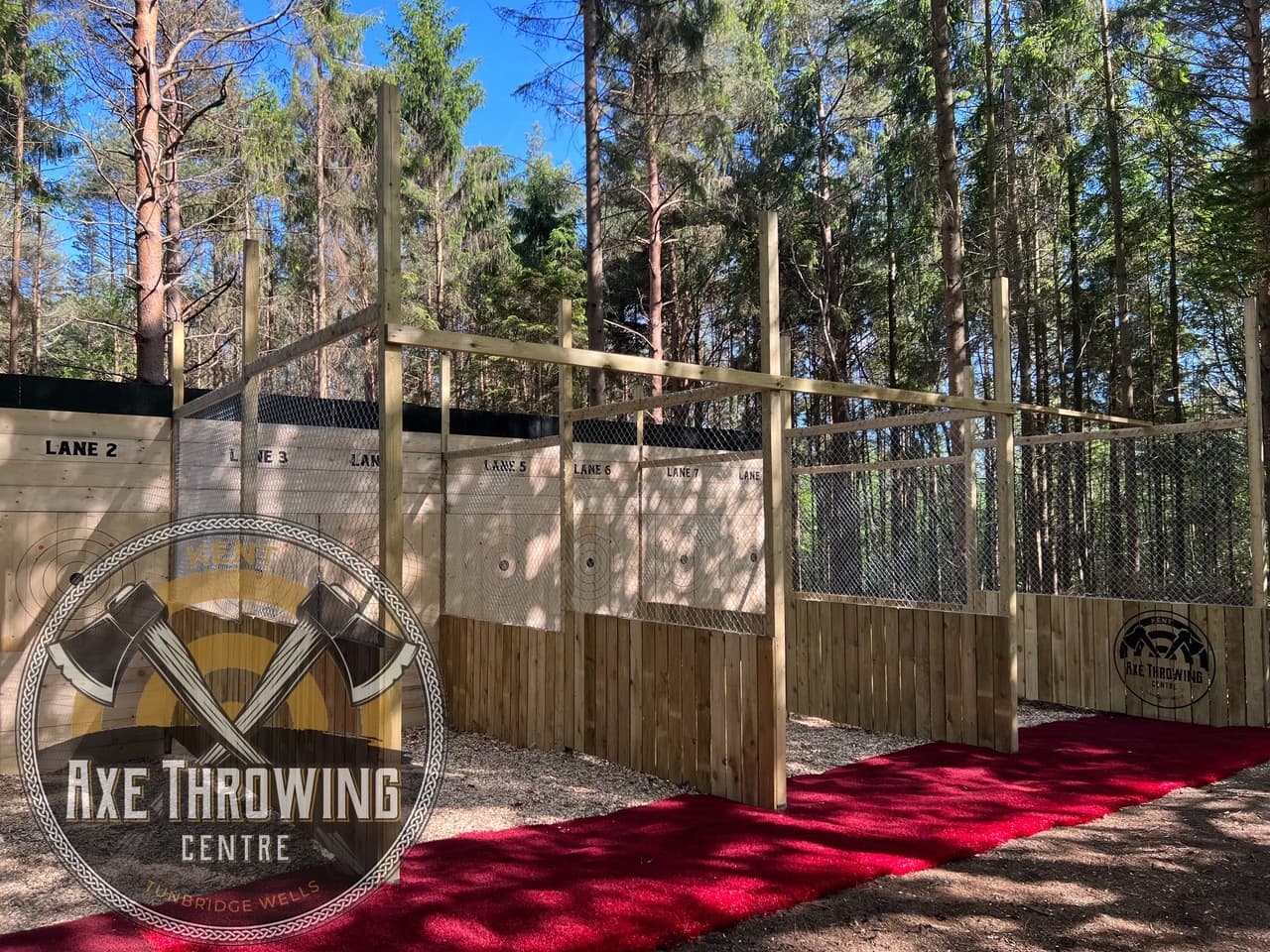 Outdoor axe throwing lanes in wooded centre with red carpet