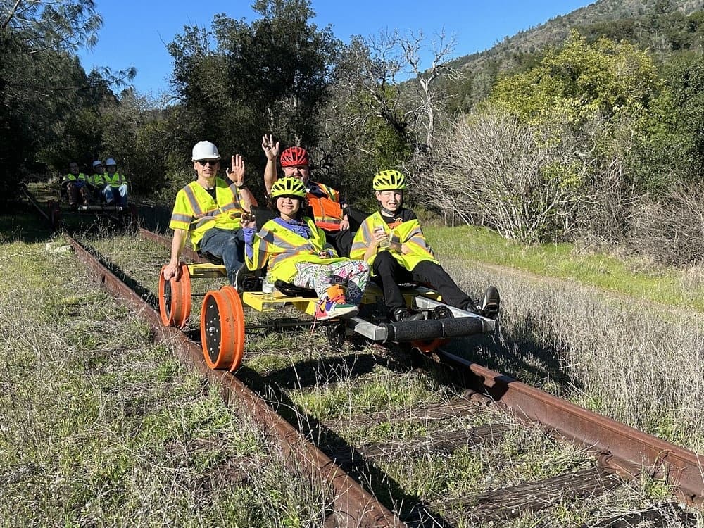 Four riders on railbike on grassy overgrown railroad in woods