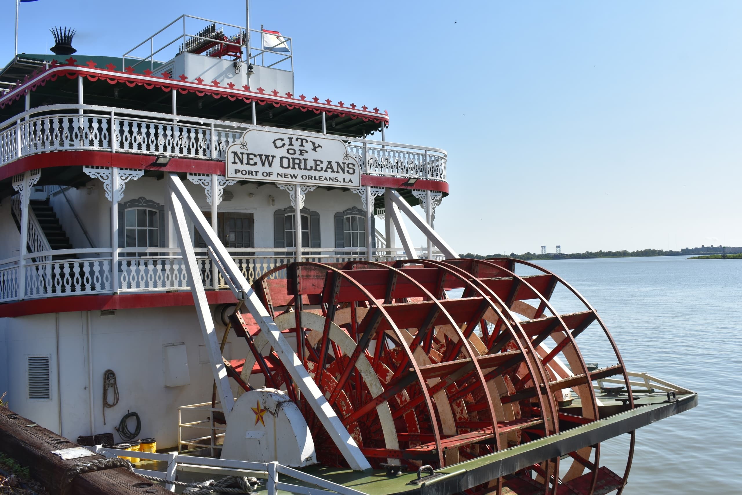 Steamboat paddlewheel cruising on river under clear blue sky