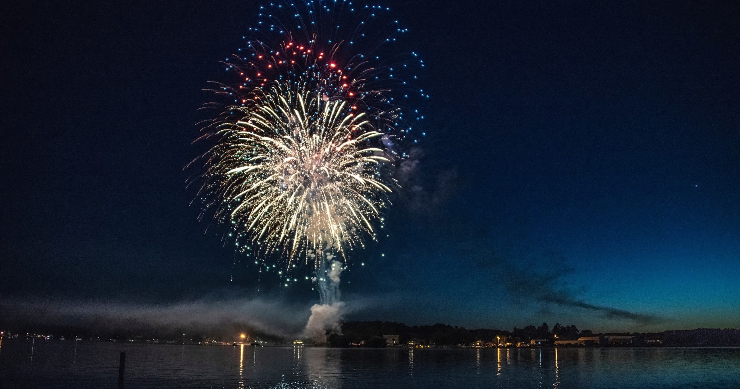 Night fireworks over Lake Erie shoreline with anchored boats