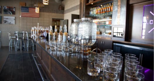 Distillery tasting room wide shot with empty bar and glassware