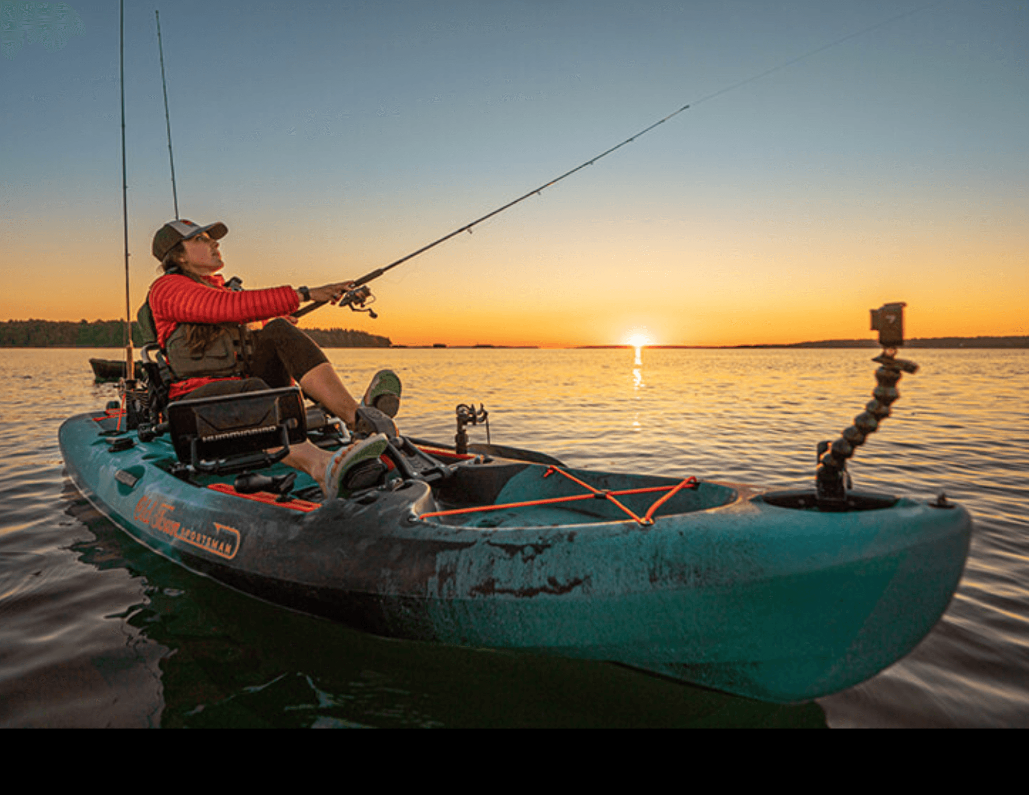Kayak angler casting at sunset on a calm lake with horizon