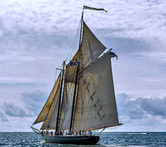 Traditional two-masted schooner sailing on choppy sea under cloudy sky