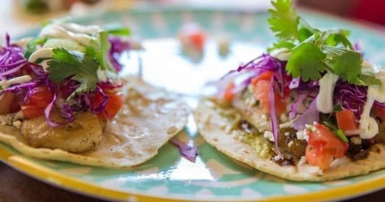 Fresh fish tacos plated with cilantro and slaw on seaside table
