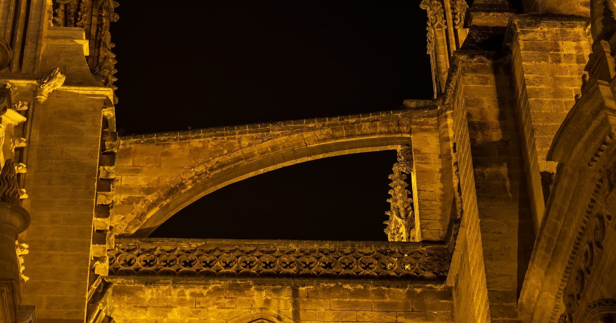 Night-time stone cathedral arches lit, architectural detail
