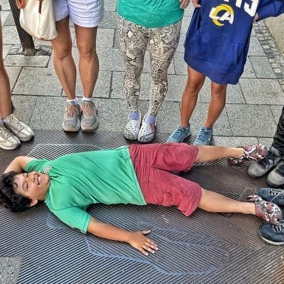Traveler lying on street grate during urban walking tour in city