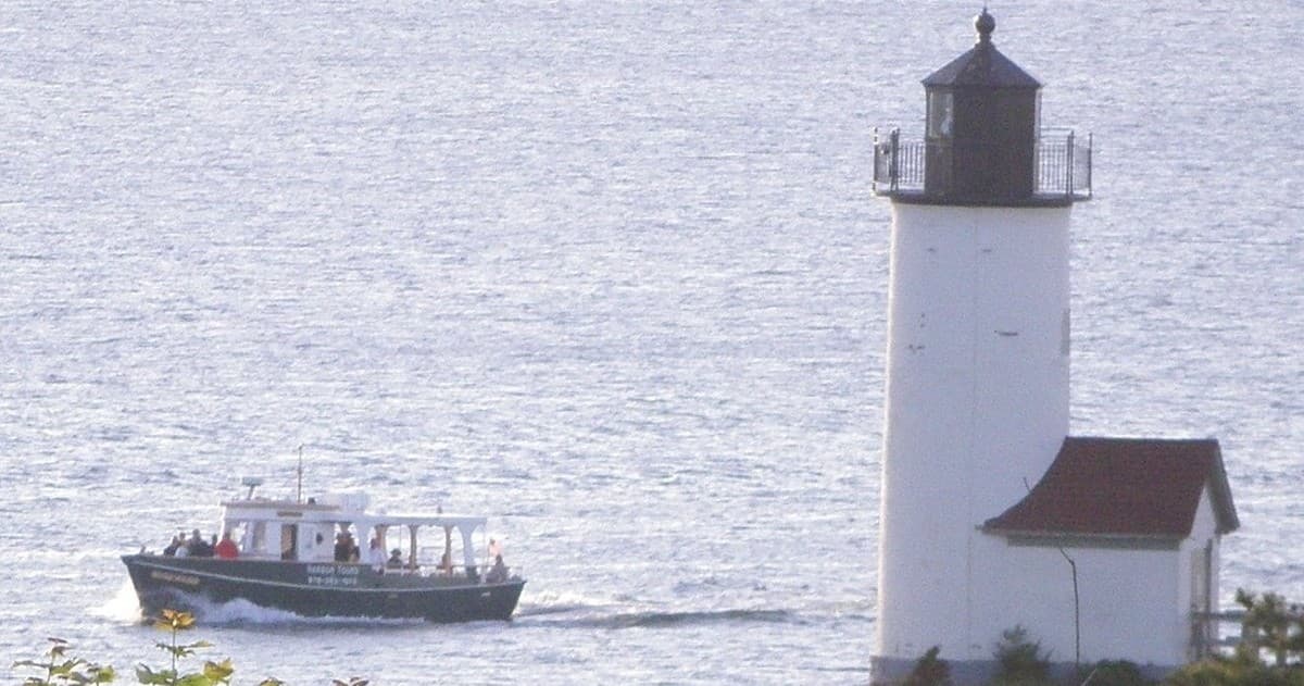 Sightseeing boat passing lighthouse off Cape Ann coastline
