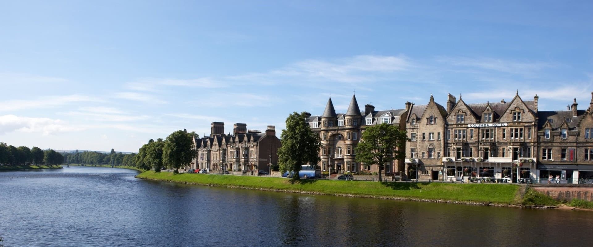 Historic riverside stone buildings and scenic riverbank in Scotland