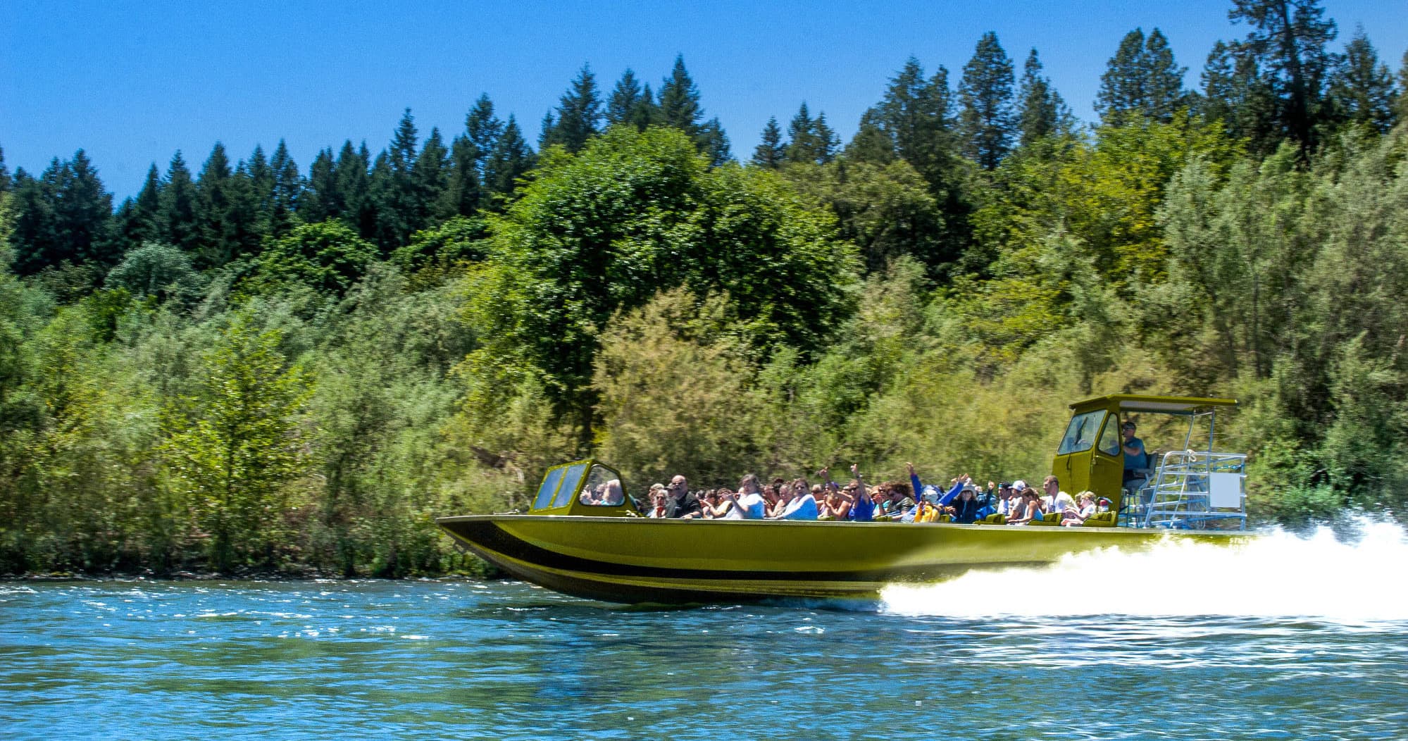 Jet boat cruising past forested riverbanks on scenic Ozarks waterway