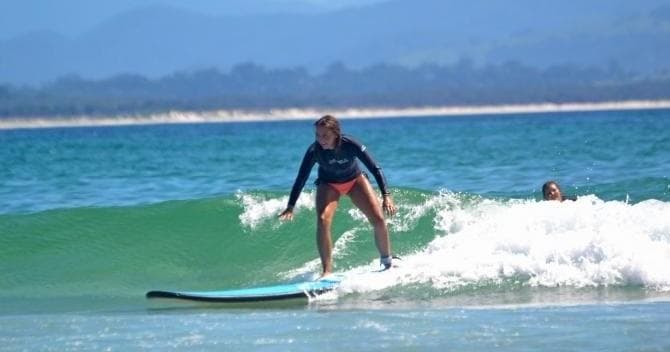 Solo surfer balancing on longboard in clear green ocean wave