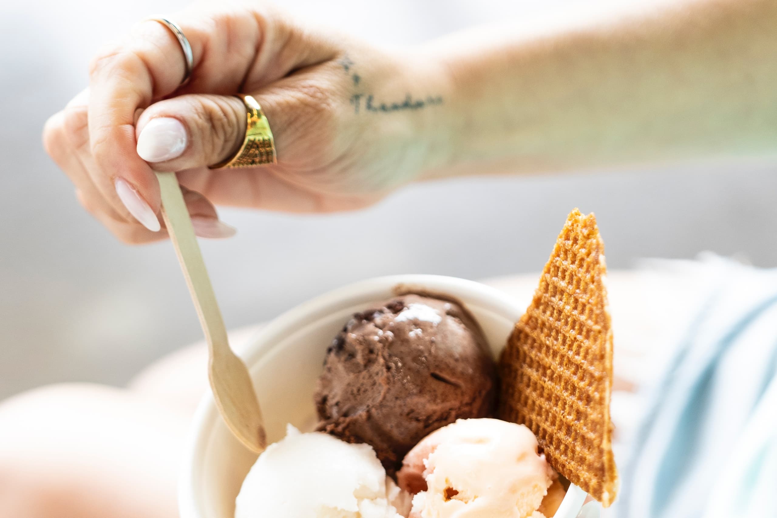 Hand holding ice cream cone on sunny seaside boardwalk