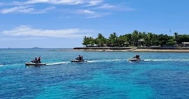 Three jet ski riders cruising turquoise reef near tropical island