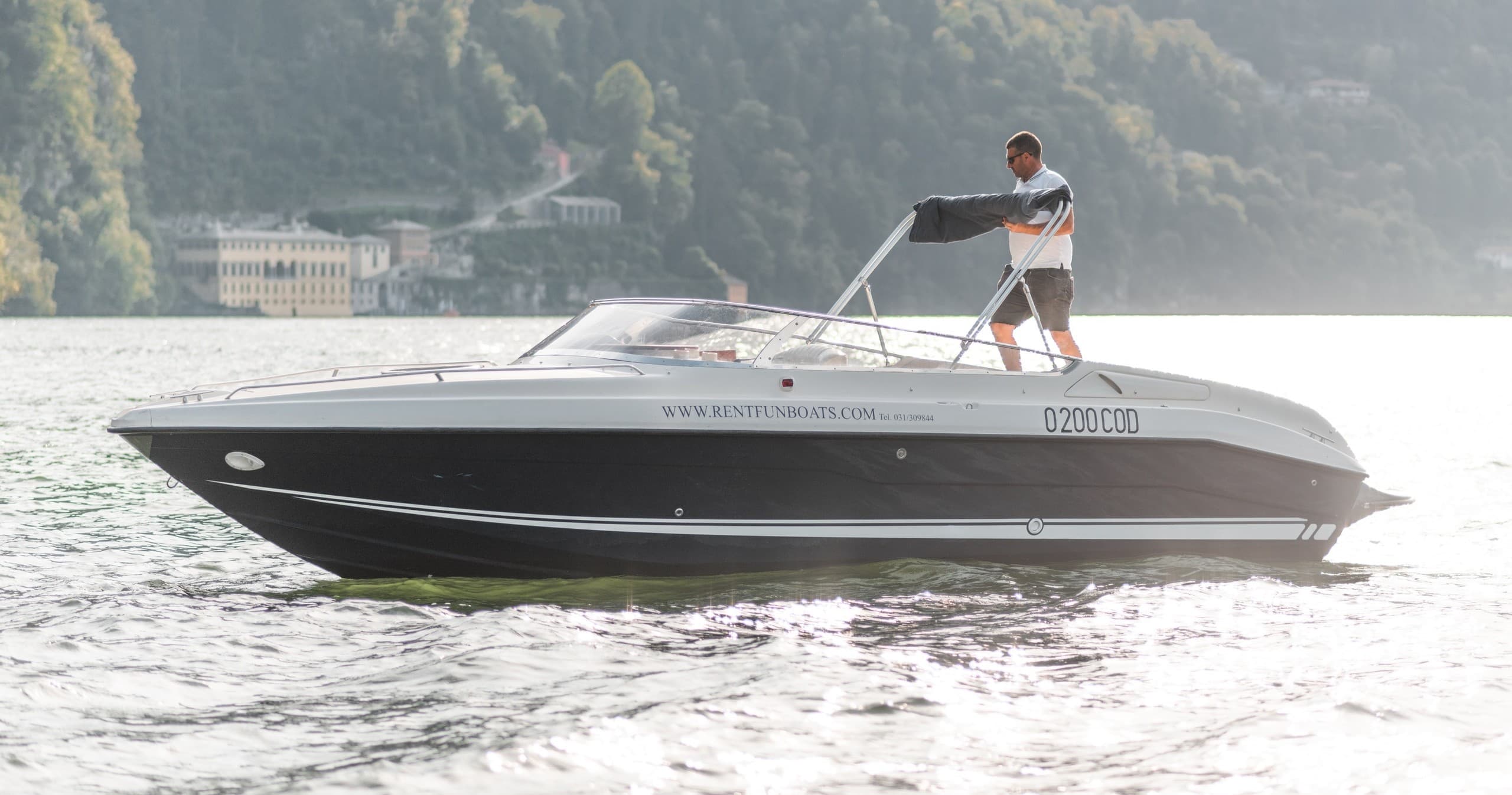 Driver piloting bowrider across sunlit lake with mountain backdrop