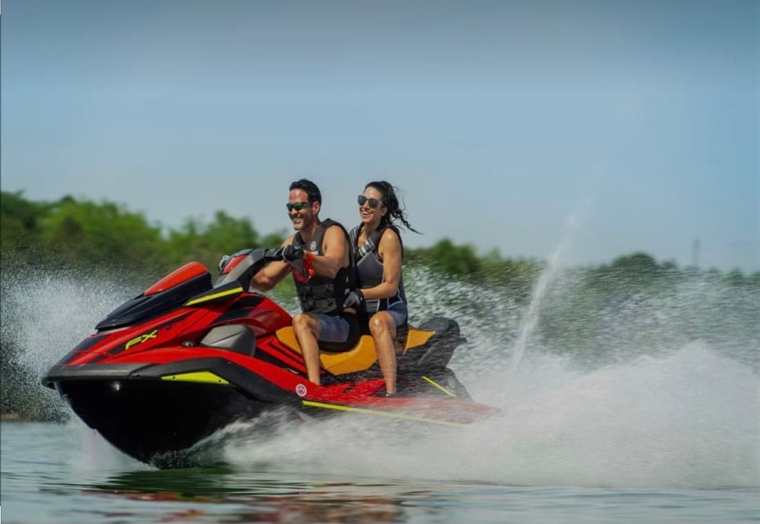 Red jet ski speeding with spray across tropical coastal water