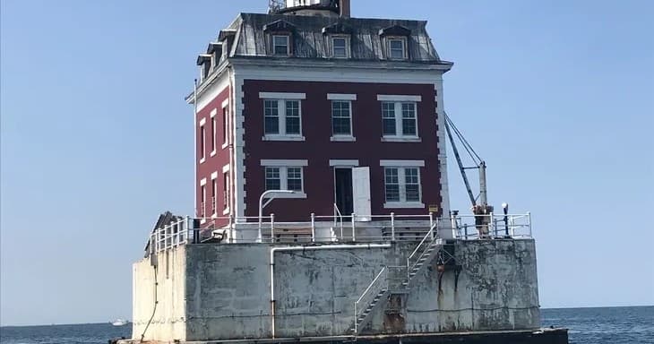 Coastal lighthouse keeper's house on sea platform, scenic boat cruise