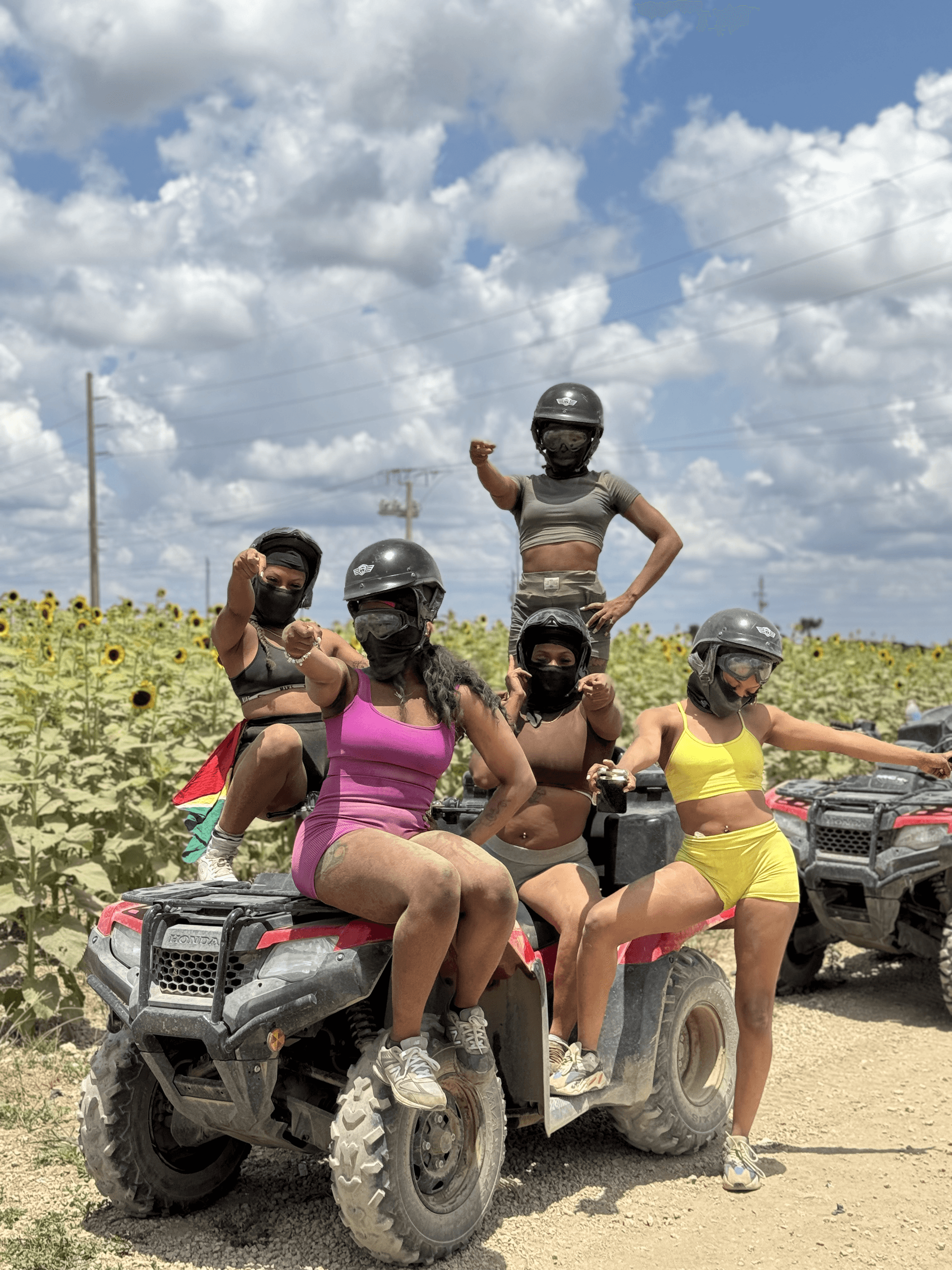 Group ATV riding through sunflower field under blue sky