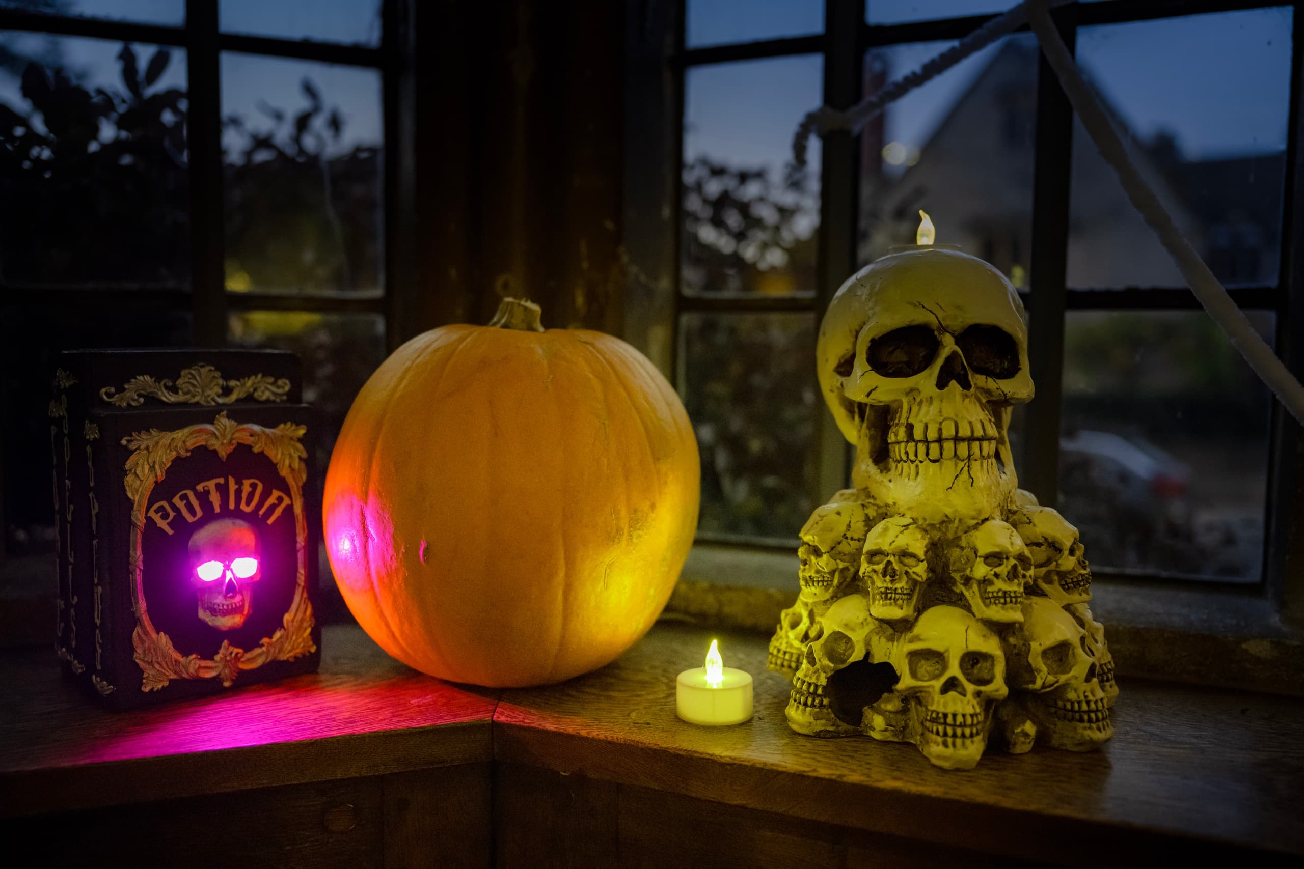Halloween display with carved pumpkin and skull by window at dusk