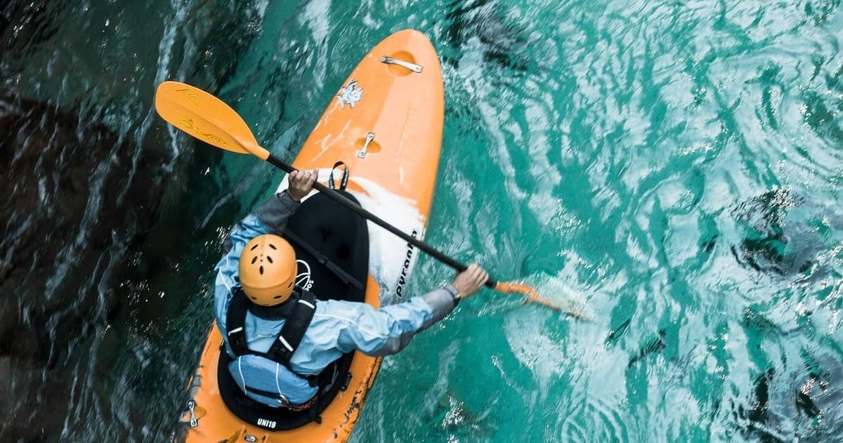 Solo kayaker paddling in clear turquoise coastal waters