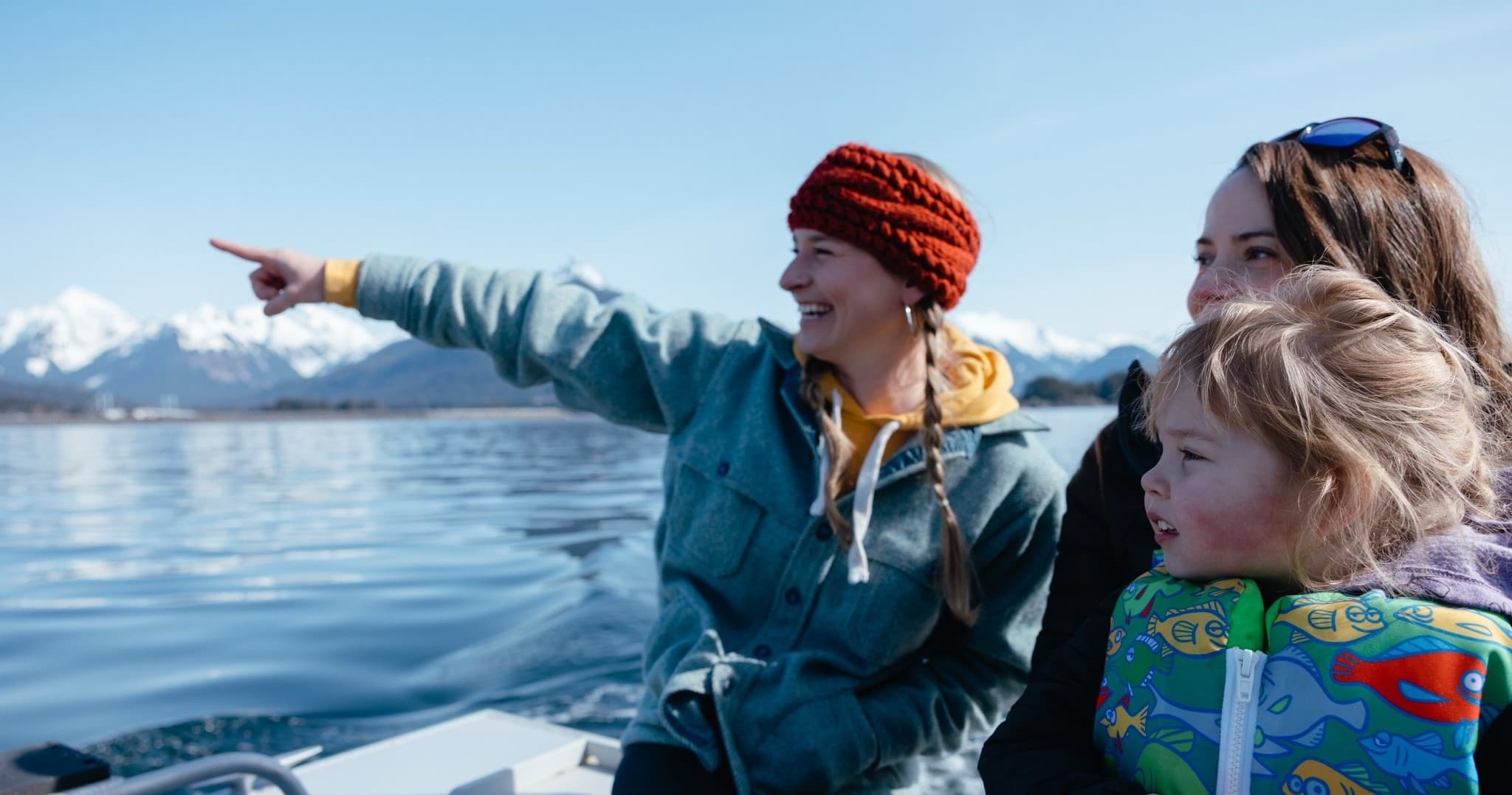 Family on wildlife boat tour near snowy Sitka, Alaska coastline