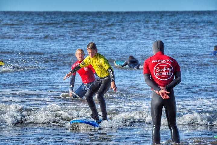 Surf instructors guiding students in shallow surf at Croyde Bay