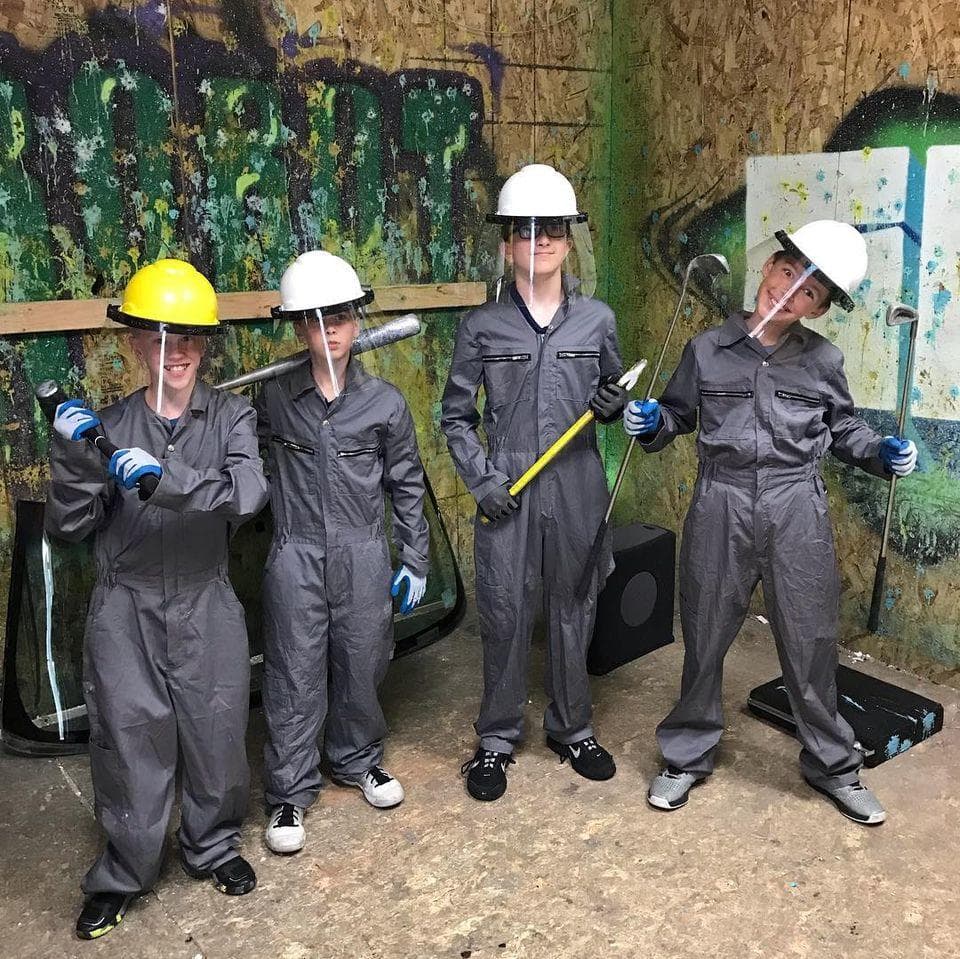 People in hard hats smashing objects in indoor rage room