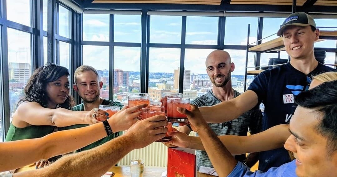 Group toasting inside rooftop venue with city skyline views