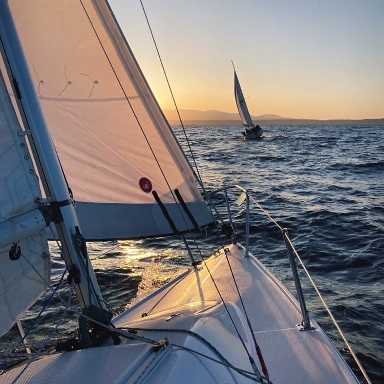 White sailboat heeling on open sea with crew trimming sails