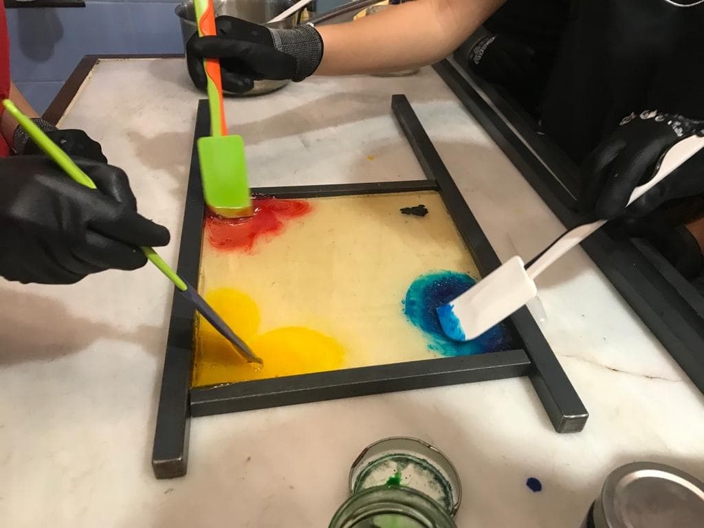 Candy workshop mixing colorful sugar pigments on flat tray