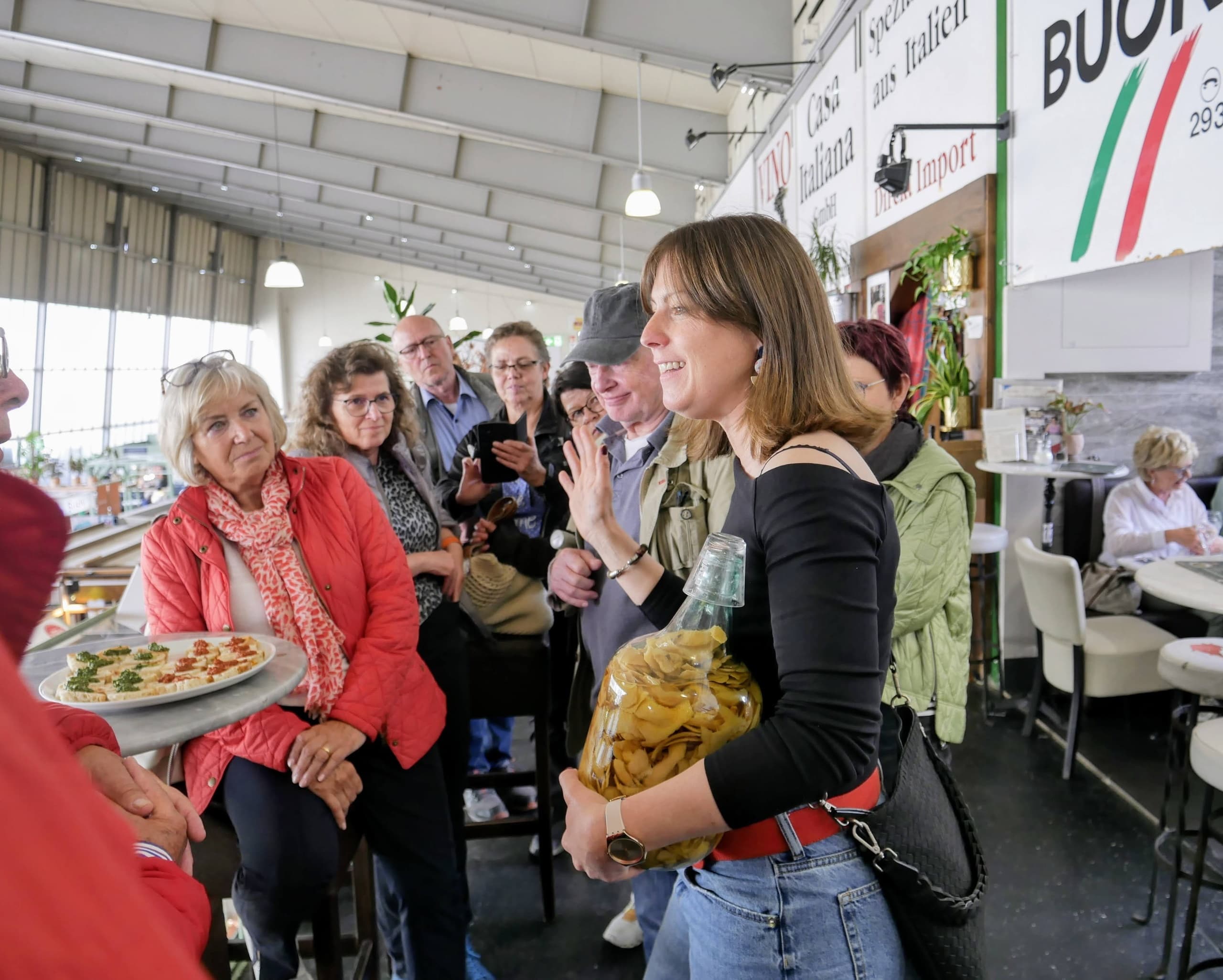 Guide presenting local food to tour group inside lively market hall