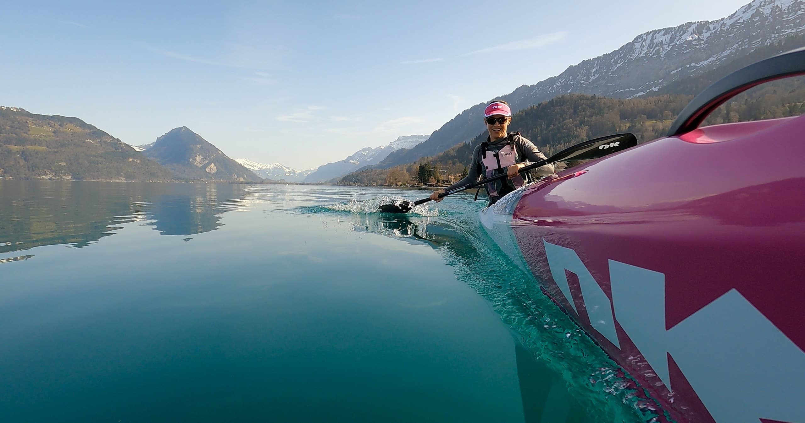 Paddler on calm turquoise lake framed by Alps and sky