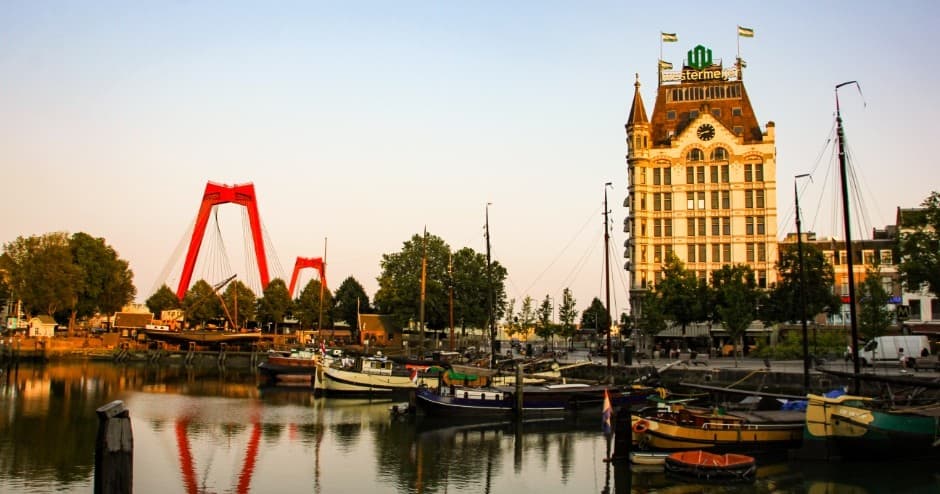 Waterfront harbor with red bridge and historic buildings at sunset