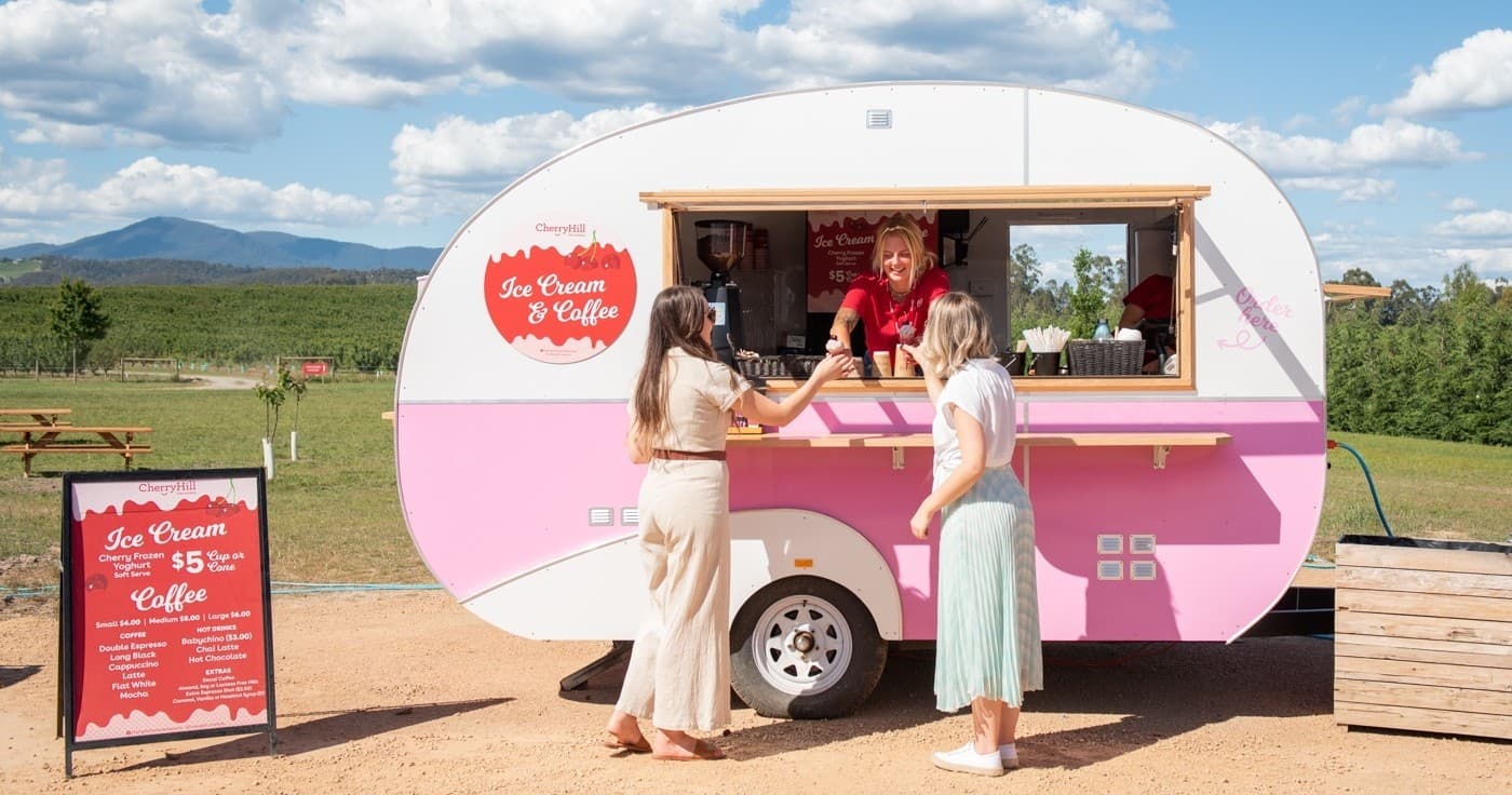 Pink food truck serving customers at rural festival field