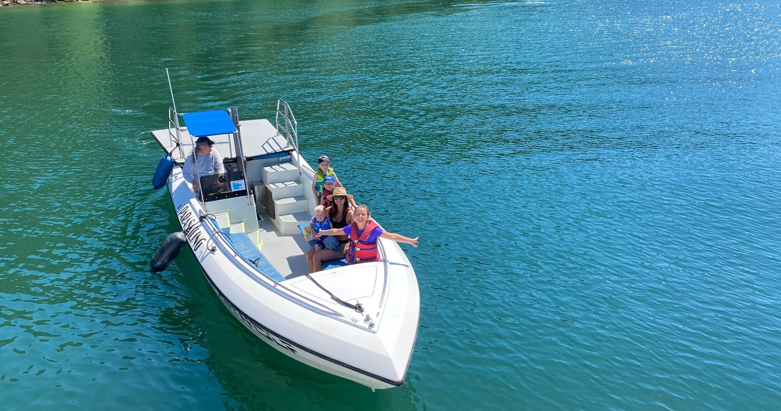 Small powerboat with passengers on clear turquoise coastal waters