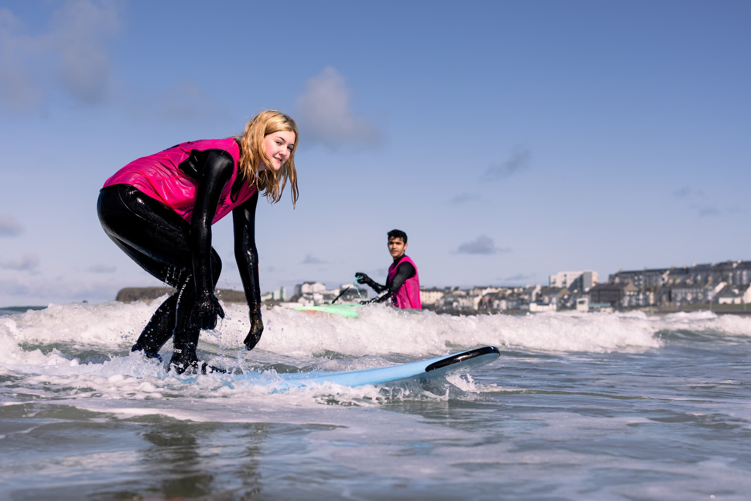 Surfer riding a breaking wave near sandy shoreline