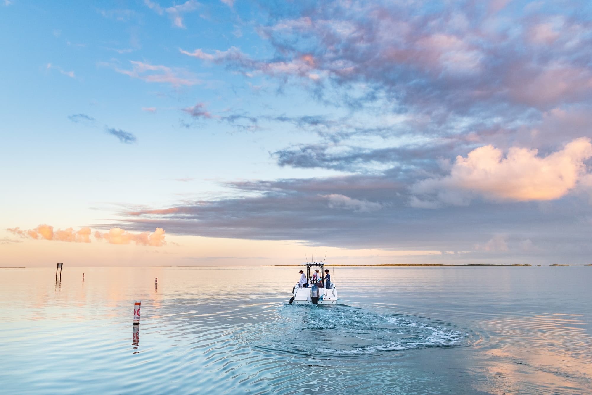 Small charter boat cruising calm coastal waters at sunrise