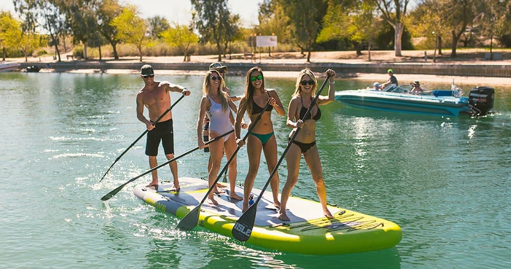 Friends stand-up paddleboarding on calm coastal bay, group outing