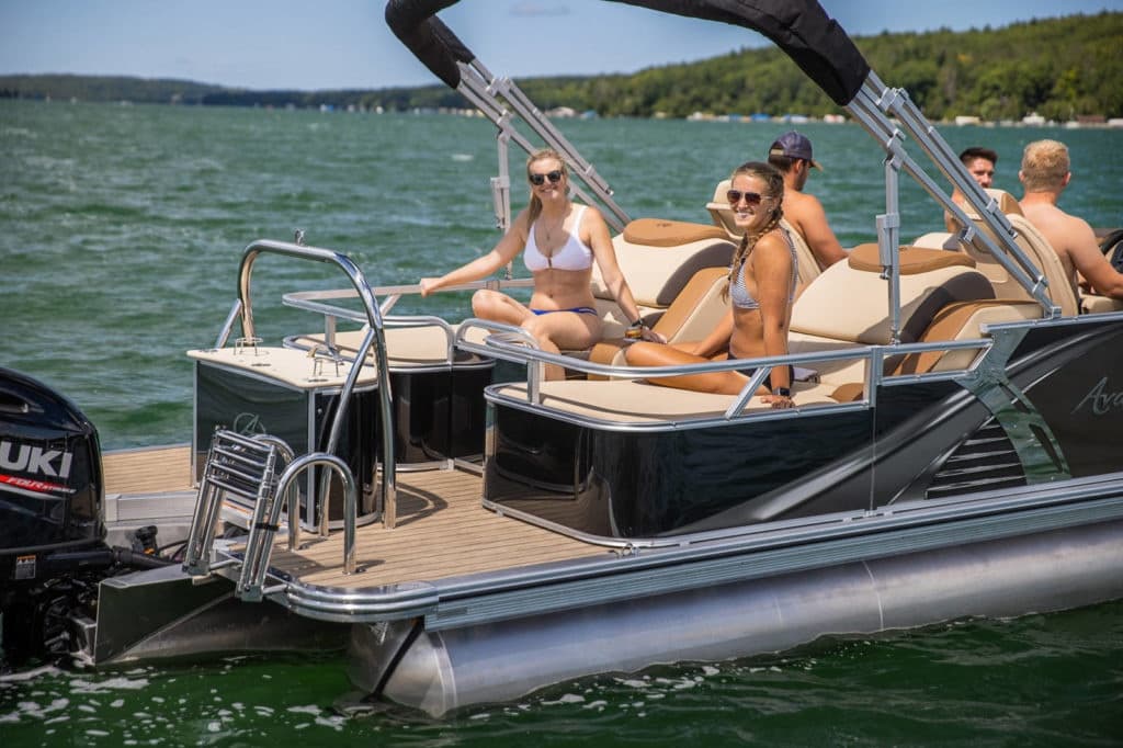 Group relaxing on pontoon boat cruising a green lake