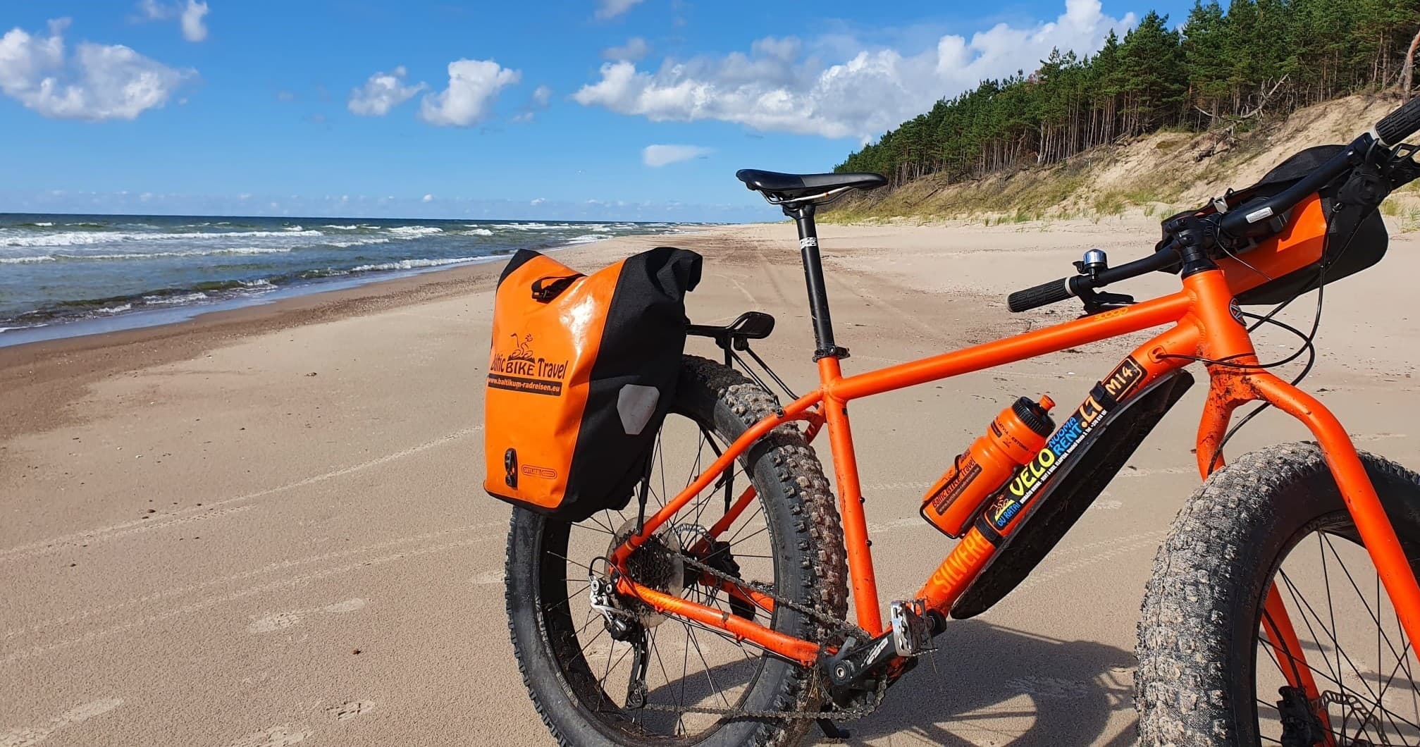 Orange fatbike parked on sandy beach for coastal bikepacking ride