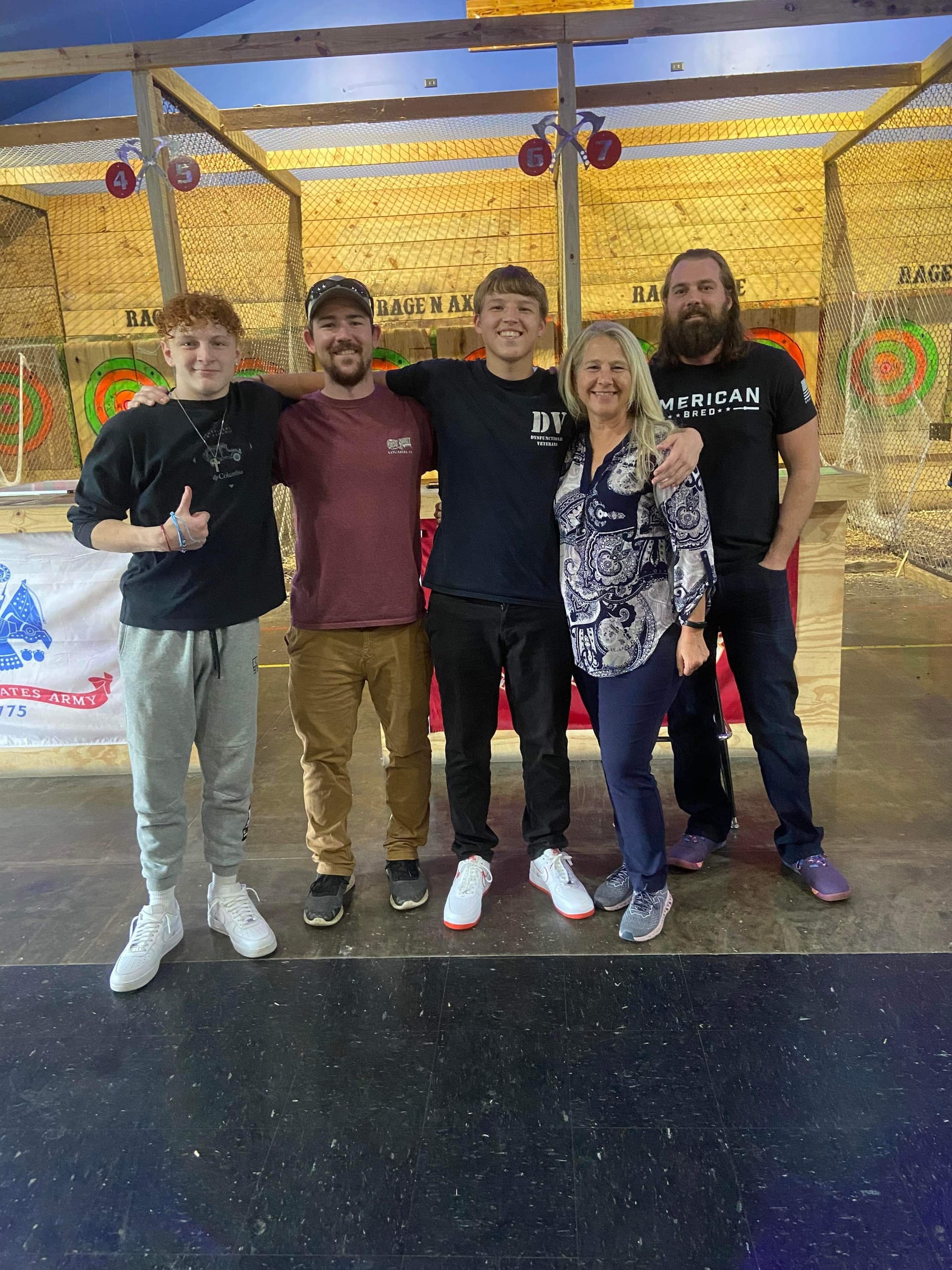 Group of friends smiling inside axe-throwing facility posing for photo