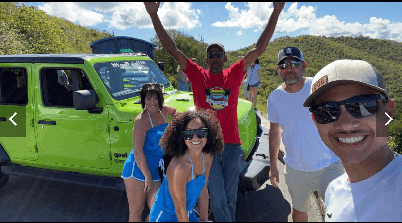 Jeep tour group posing by bright green Jeep with scenic island hills