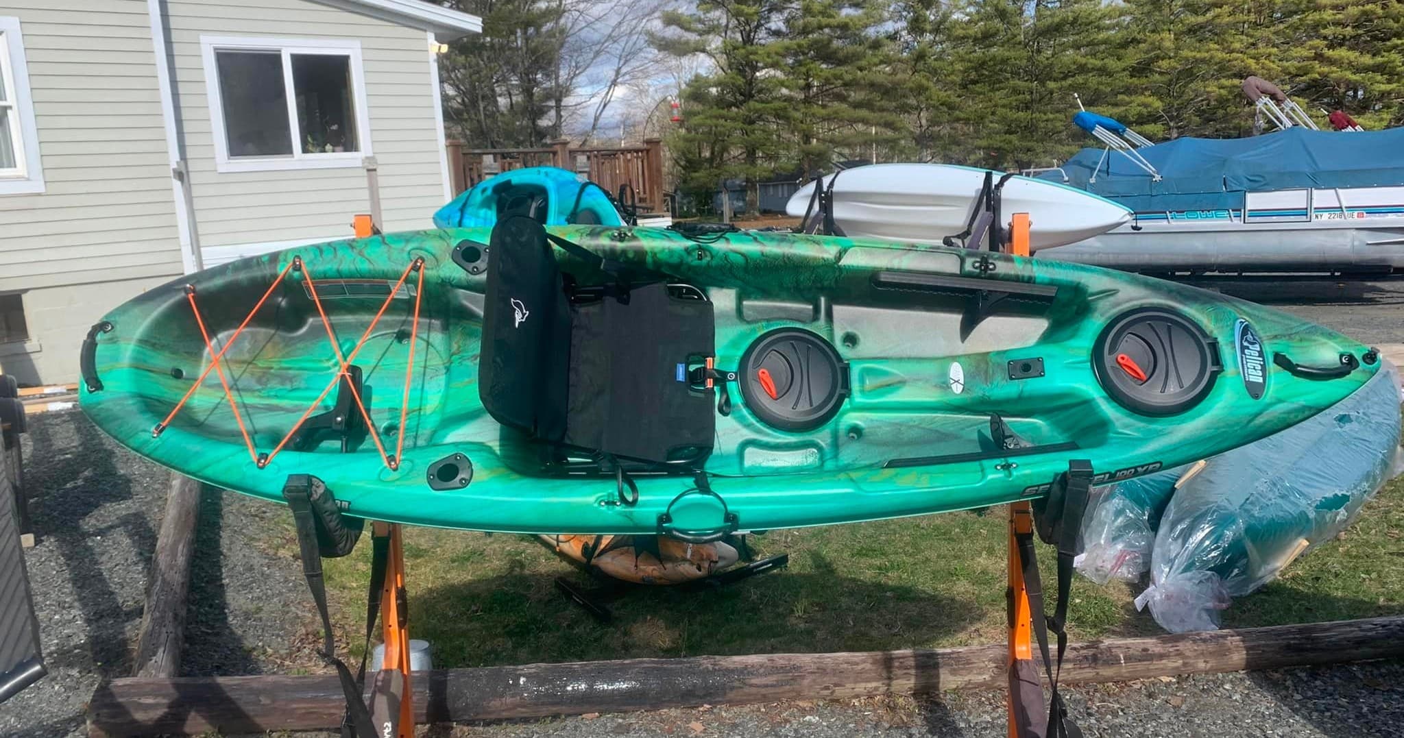 Single sit-on-top kayak on rack by marina, lake paddling prep